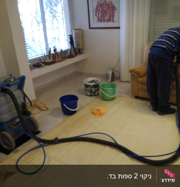 אדם מנקה ספה עם מכונת ניקוי ושואב אבק